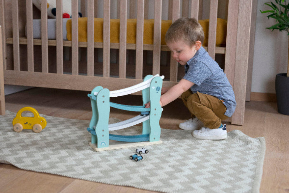 Ein kleiner Junge spielt mit der türkisen Autorutsche.