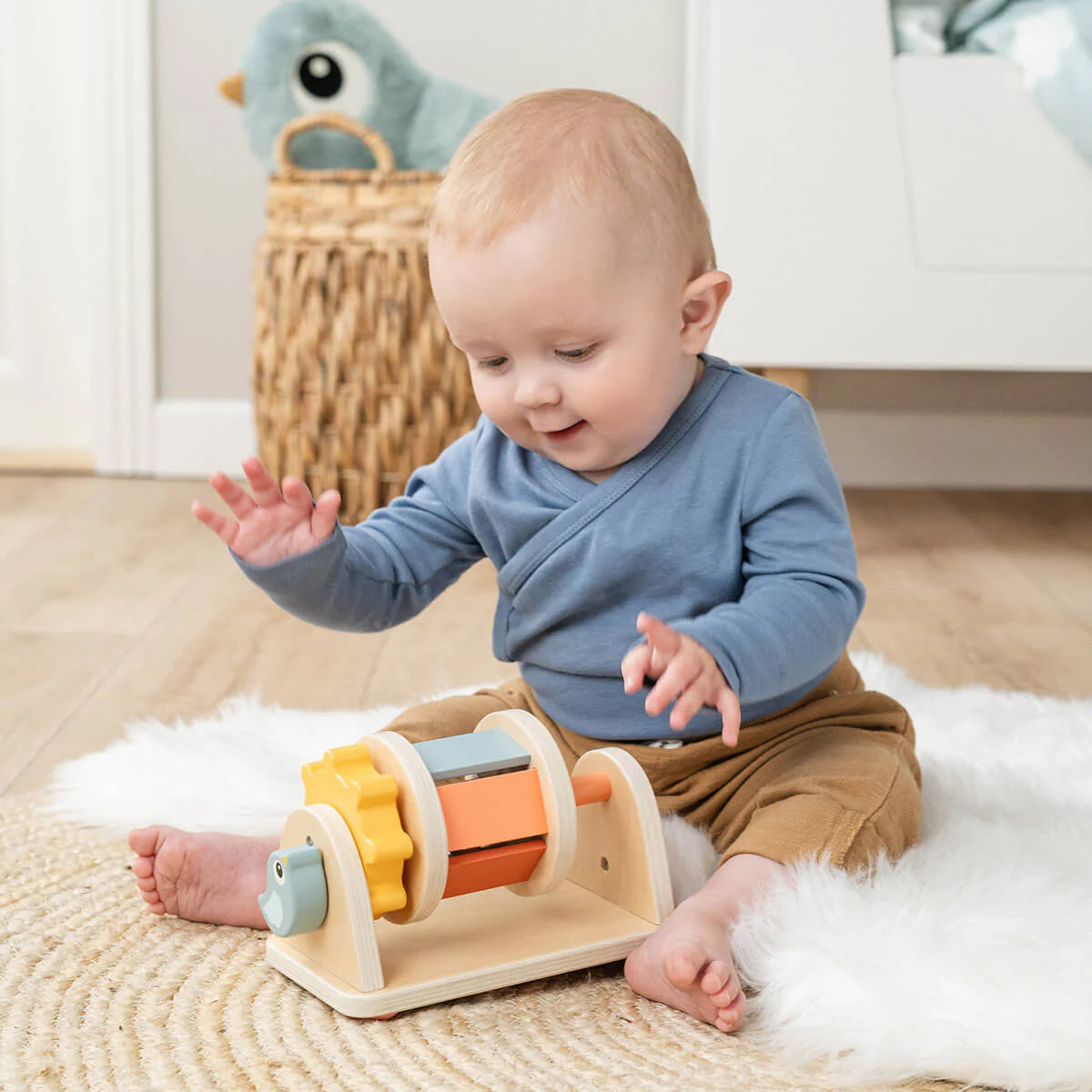 Ein kleines Baby spielt auf einem Teppich mit dem Aktivitätsspielzeug.