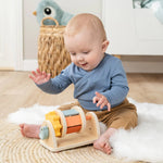 Ein kleines Baby spielt auf einem Teppich mit dem Aktivitätsspielzeug.