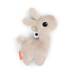 Eine kleine Rassel in beige in der Form eines Lamals mit geöffneten Auge.